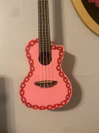 a pink ukulele hanging on a wall